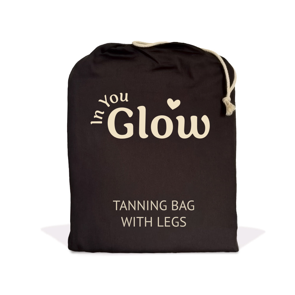 A black drawstring tanning bag with cream-colored text reading 'In You Glow' and 'TANNING BAG WITH LEGS' on a white background.